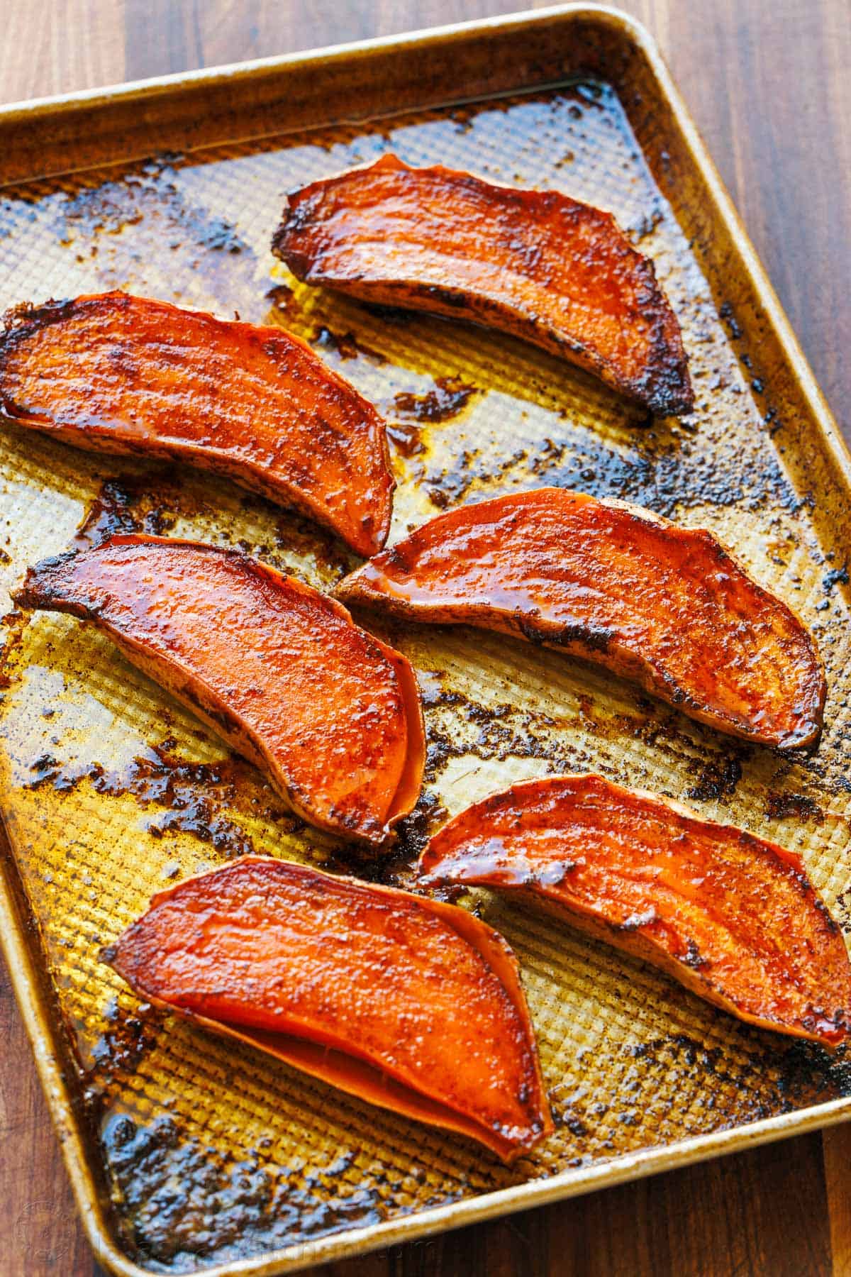 Tray of caramelized roasted sweet potato halves fresh out of the oven with crispy roasted sides.