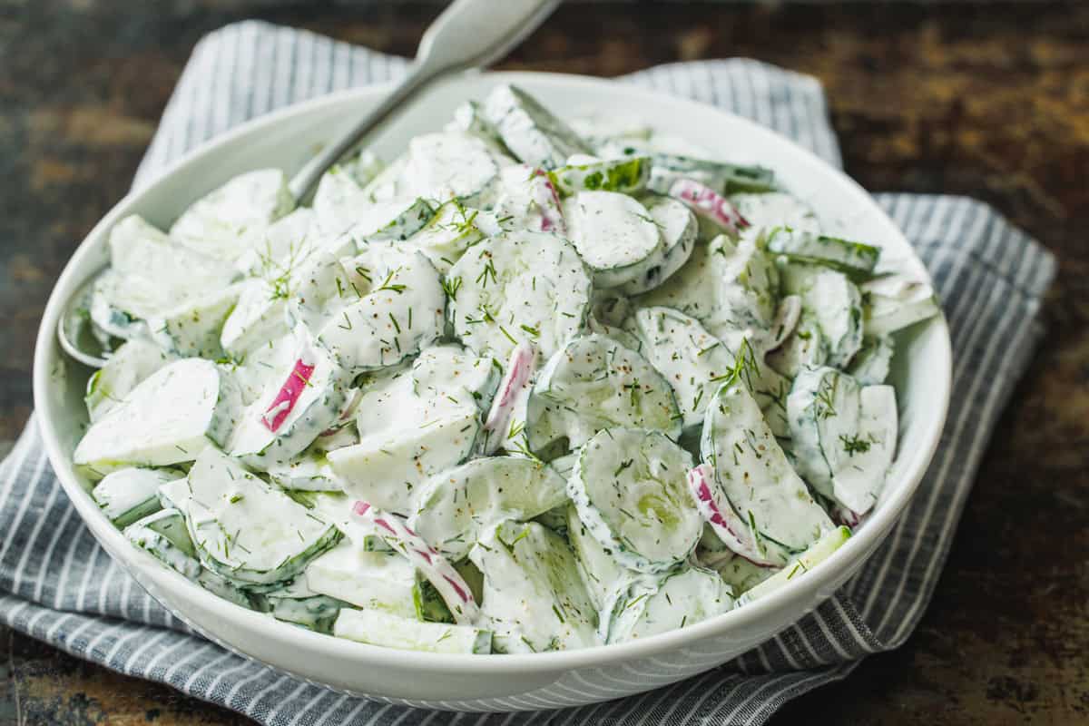 Creamy cucumber salad in a bowl with a serving spoon