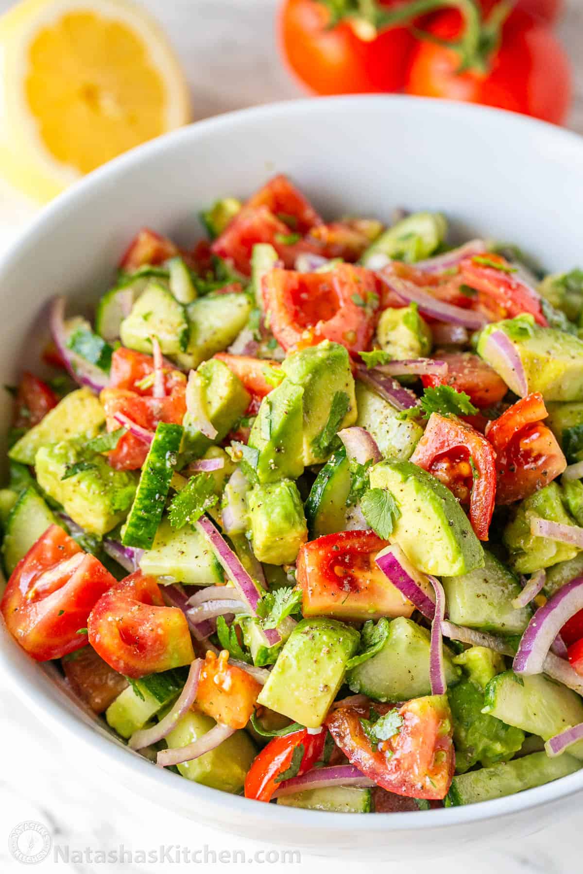 Prepared cucumber tomato avocado salad served in a white mixing bowl