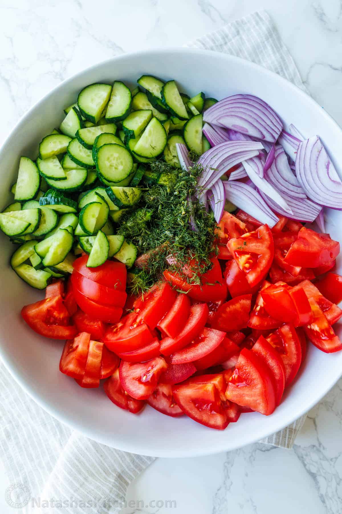 bowl of cucumber tomato salad with cucumbers, red onion, tomato, and fresh dill