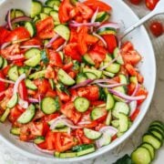 Cucumber Tomato Salad recipe in a white bowl with red onions and dill, oil and vinegar dressing