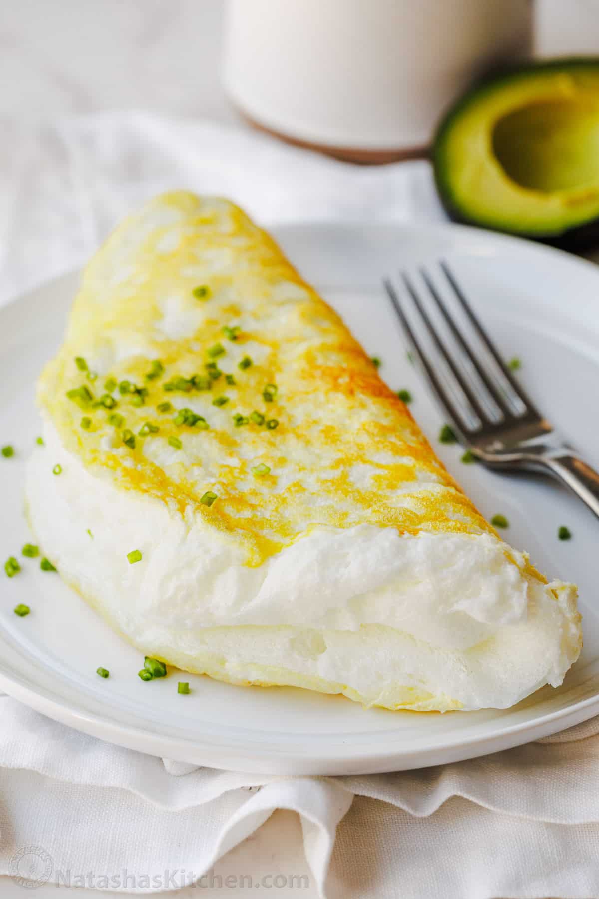 Make a fluffy egg white omelette in just 10 minutes with 4 ingredients. It’s light, airy, high-protein, and easy to customize with toppings. Fluffy egg white omelette on a white plate with fork and chives to garnish