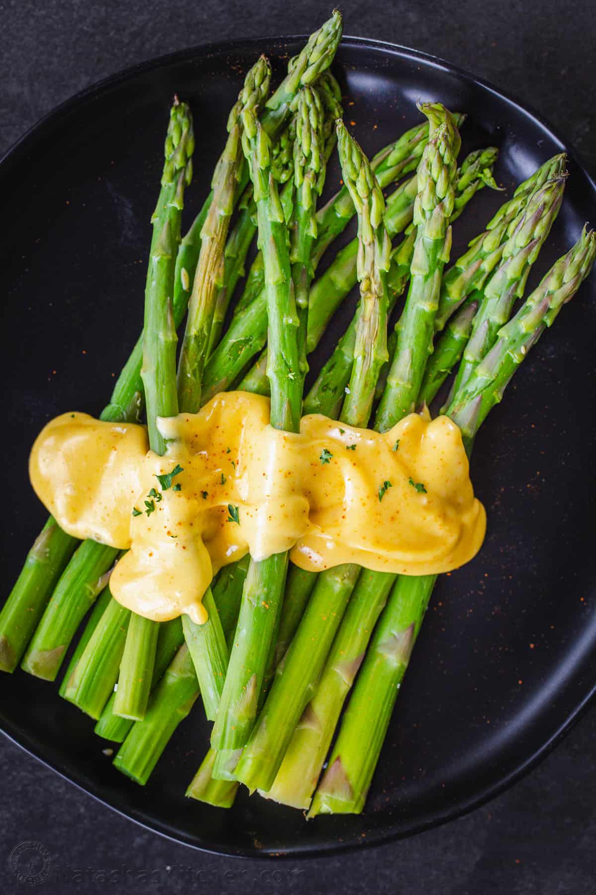 Asparagus served with yellow sauce and garnished with parsley