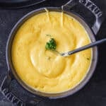 Hollandaise Sauce Recipe stirred in a black serving dish with black spoon and parsley garnish