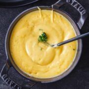 Hollandaise Sauce Recipe stirred in a black serving dish with black spoon and parsley garnish