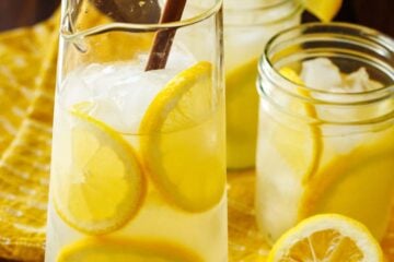 Homemade Lemonade recipe over ice with lemon rounds and mason jars