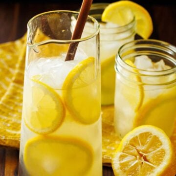 Homemade Lemonade recipe over ice with lemon rounds and mason jars