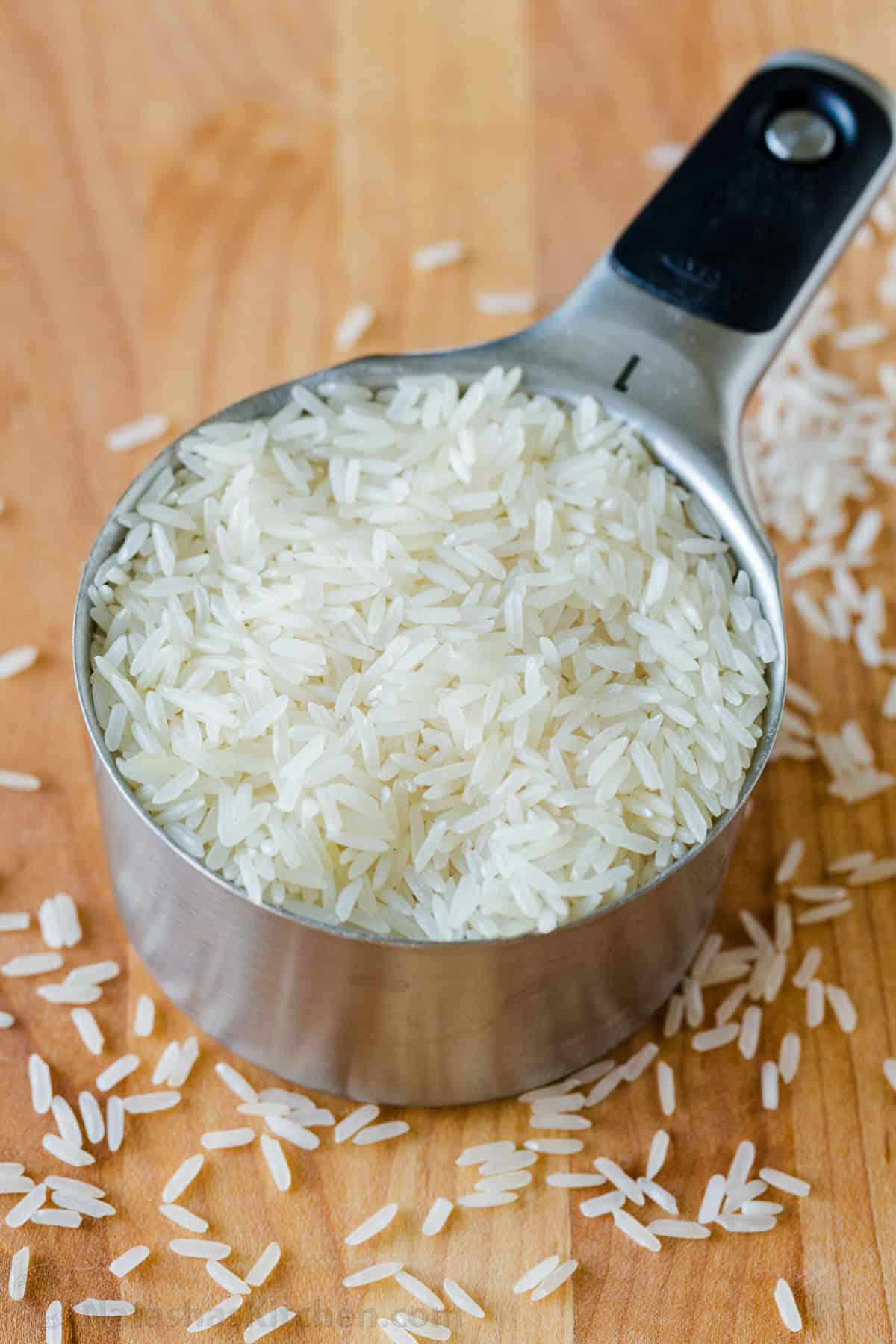 How to cook rice perfectly every time with the best rice-to-water ratio and a foolproof stovetop method for fluffy white rice. Get the recipe! Uncooked white rice in a measuring cup with rice surrounding the base