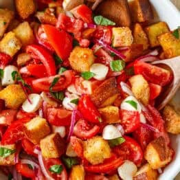 Panzanella Salad served in a white serving bowl garnished with basil