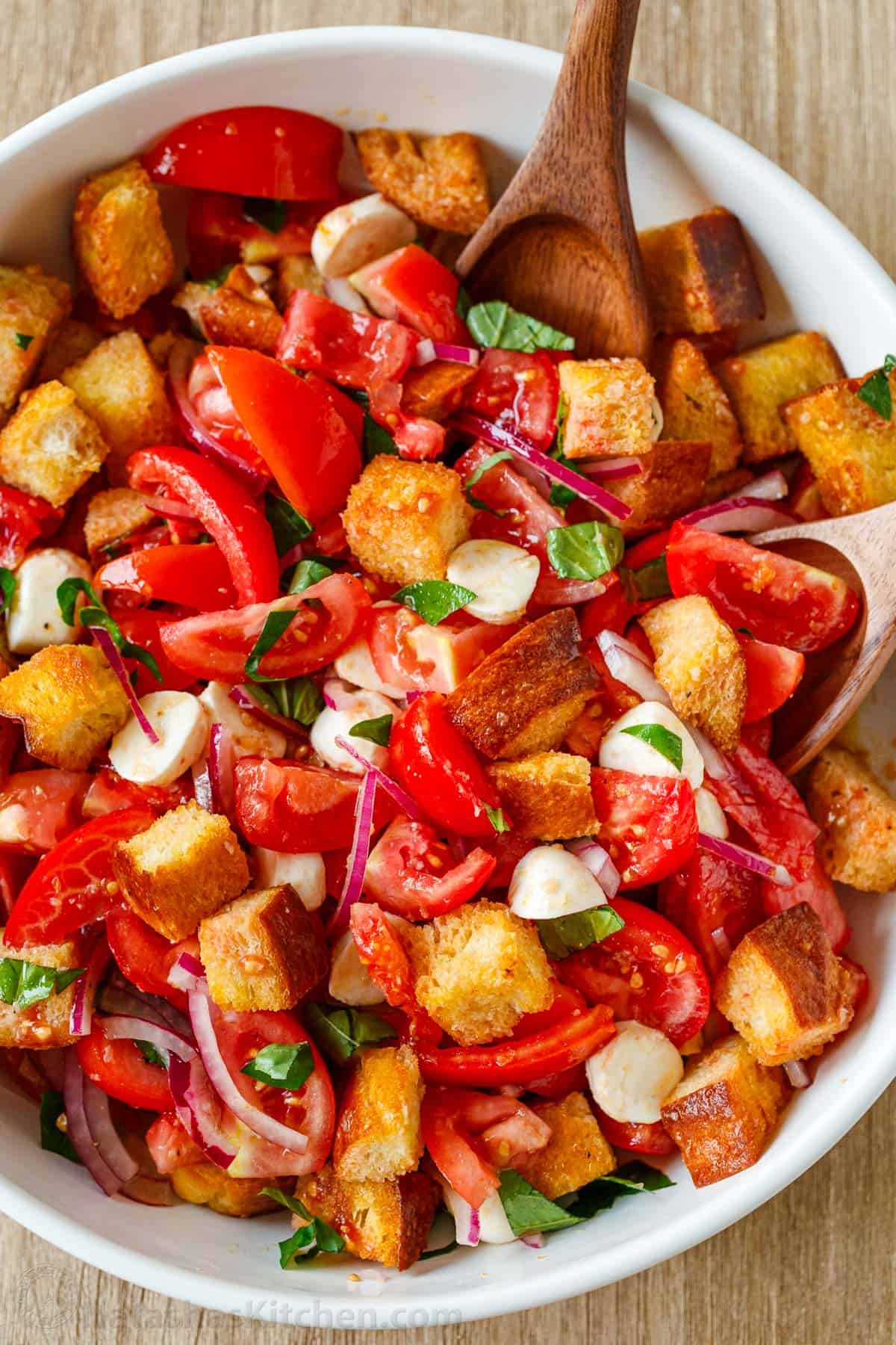 This easy Panzanella Salad is a Tuscan bread salad with juicy tomatoes, crisp leftover bread, fresh basil, mozzarella, and bright vinaigrette. Panzanella Salad served in a white serving bowl garnished with basil