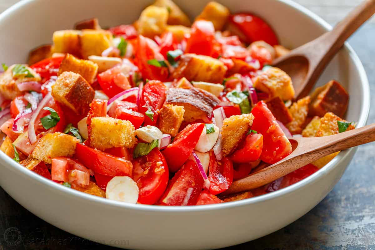 This easy Panzanella Salad is a Tuscan bread salad with juicy tomatoes, crisp leftover bread, fresh basil, mozzarella, and bright vinaigrette. Panzanella Salad tossed together in a serving bowl