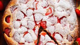 Easy Strawberry cake with a slice cut out surrounded by fresh strawberries