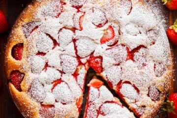 Easy Strawberry cake with a slice cut out surrounded by fresh strawberries