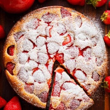 Easy Strawberry cake with a slice cut out surrounded by fresh strawberries