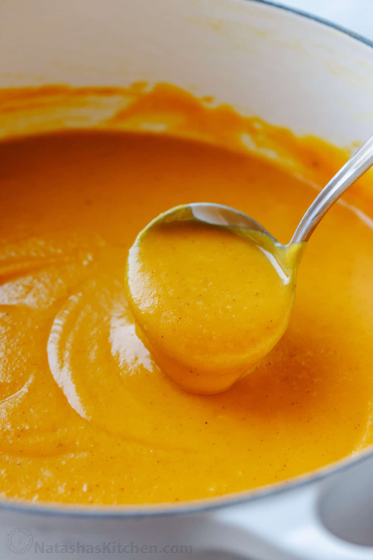 Easy Butternut Squash Soup recipe made from roasted butternut squash that's blended into a creamy soup and topped with maple syrup and bacon. Creamy roasted butternut squash soup in a pot with a ladle
