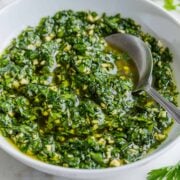Chimichurri sauce in a white serving bowl with spoon