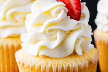 Cupcake frosting piped onto a vanilla cupcake topped with a strawberry