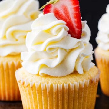 Cupcake frosting piped onto a vanilla cupcake topped with a strawberry
