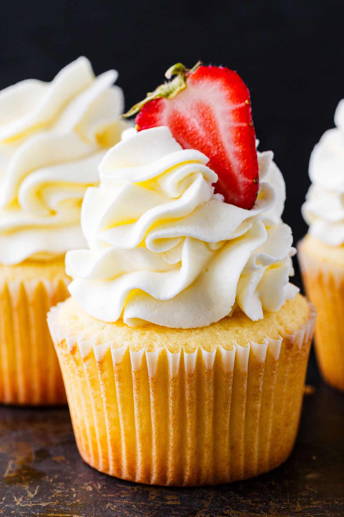 This easy cupcake frosting is light, fluffy, and not too sweet. Made with 5 ingredients, it pipes beautifully onto cupcakes and cakes. Cupcake frosting piped onto a vanilla cupcake topped with a strawberry