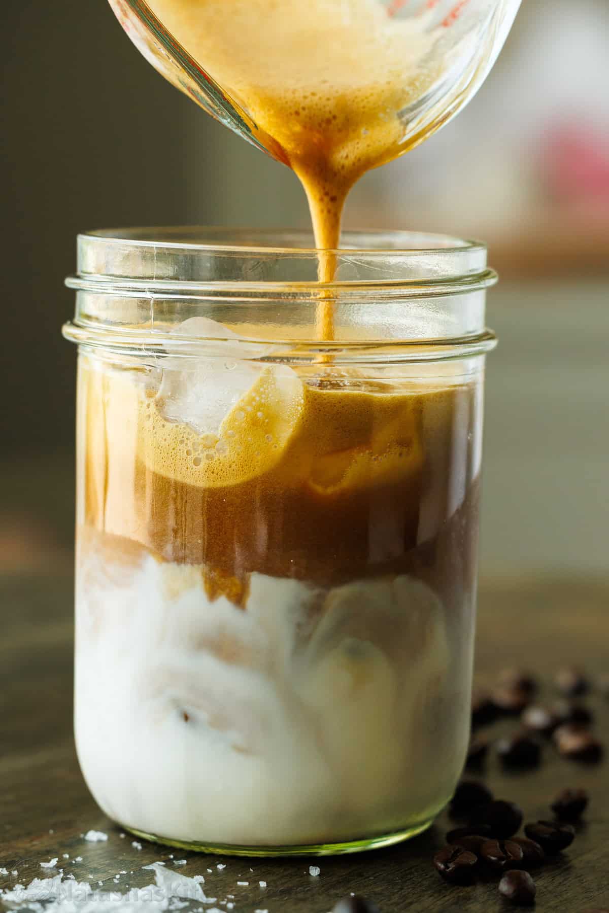 Pouring Iced Maple Latte from a mixing glass into a mason jar