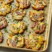 Smashed potatoes appetizer recipe on a gold sheet pan with crispy edges