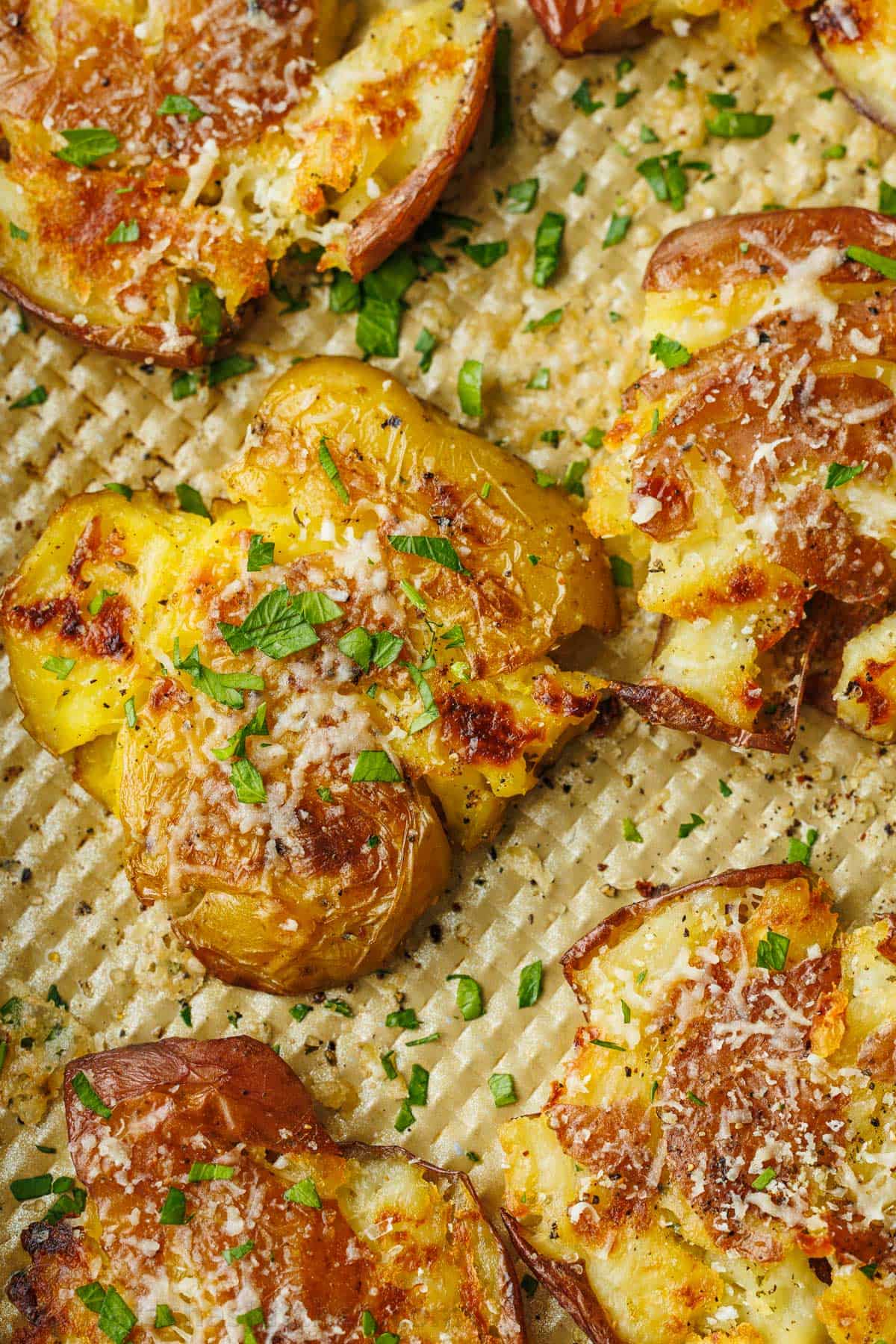 close up of smashed potatoes recipe topped with Parmesan cheese and parsley