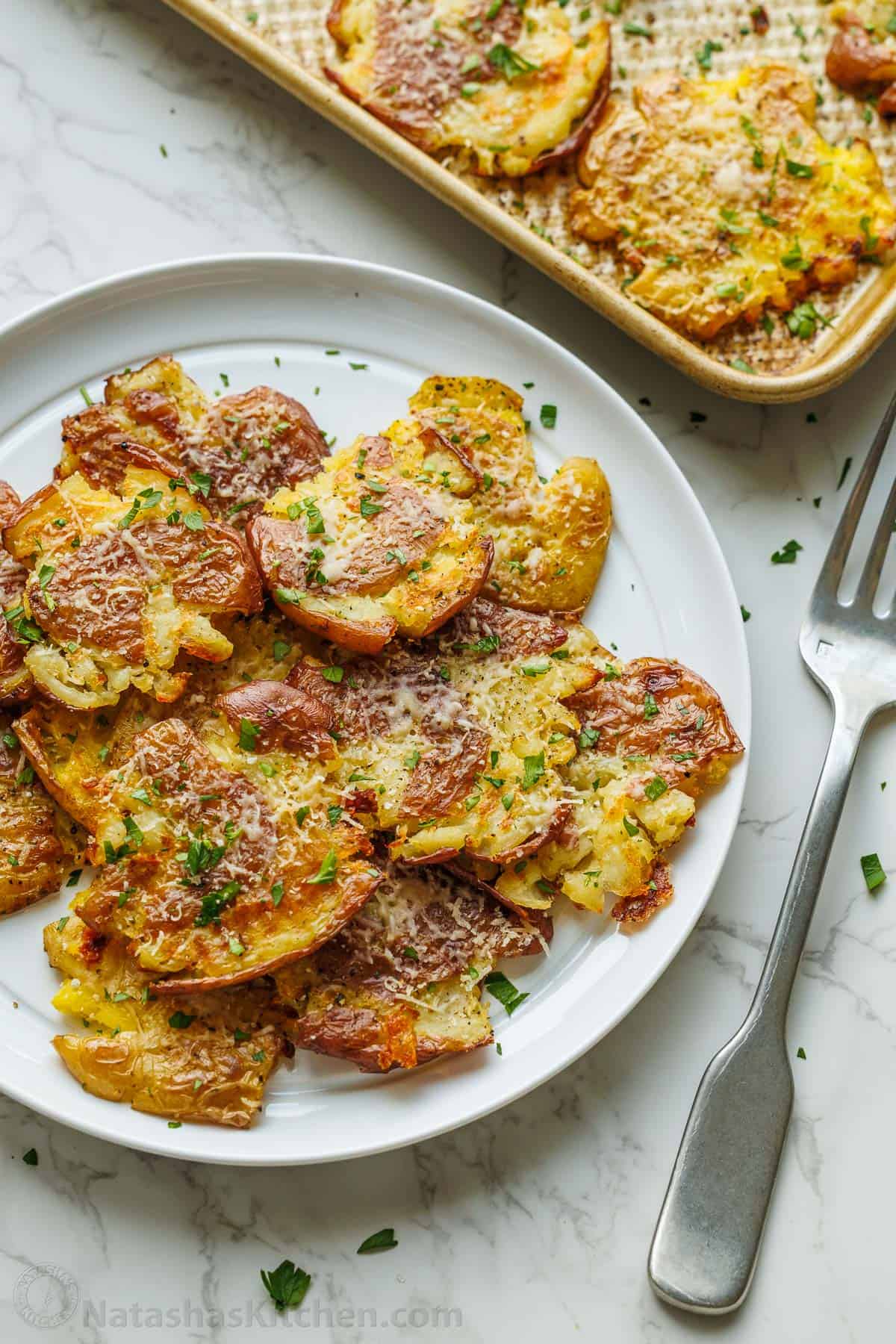 smashed potatoes appetizer on a white plate with fork
