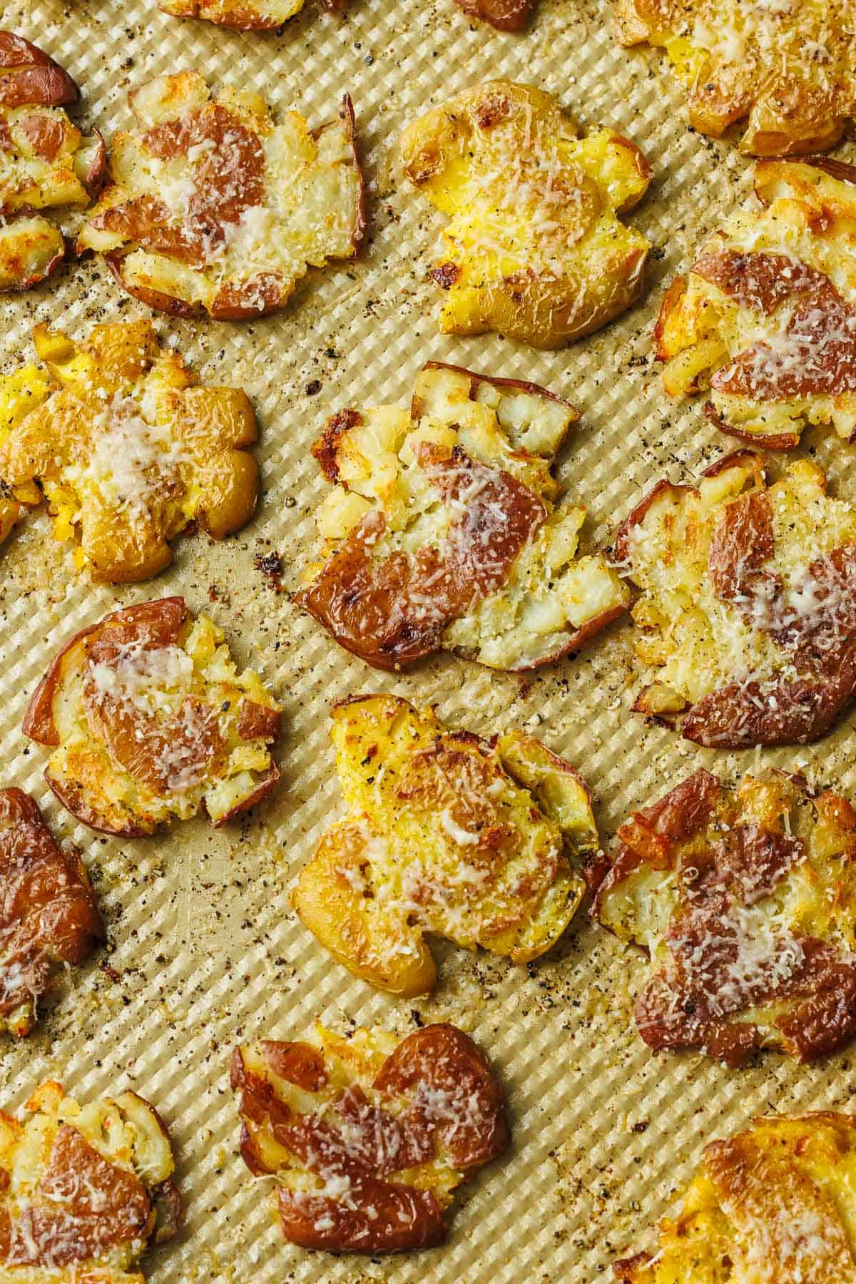 smashed potatoes on a sheet pan with Parmesan cheese sprinkled on top