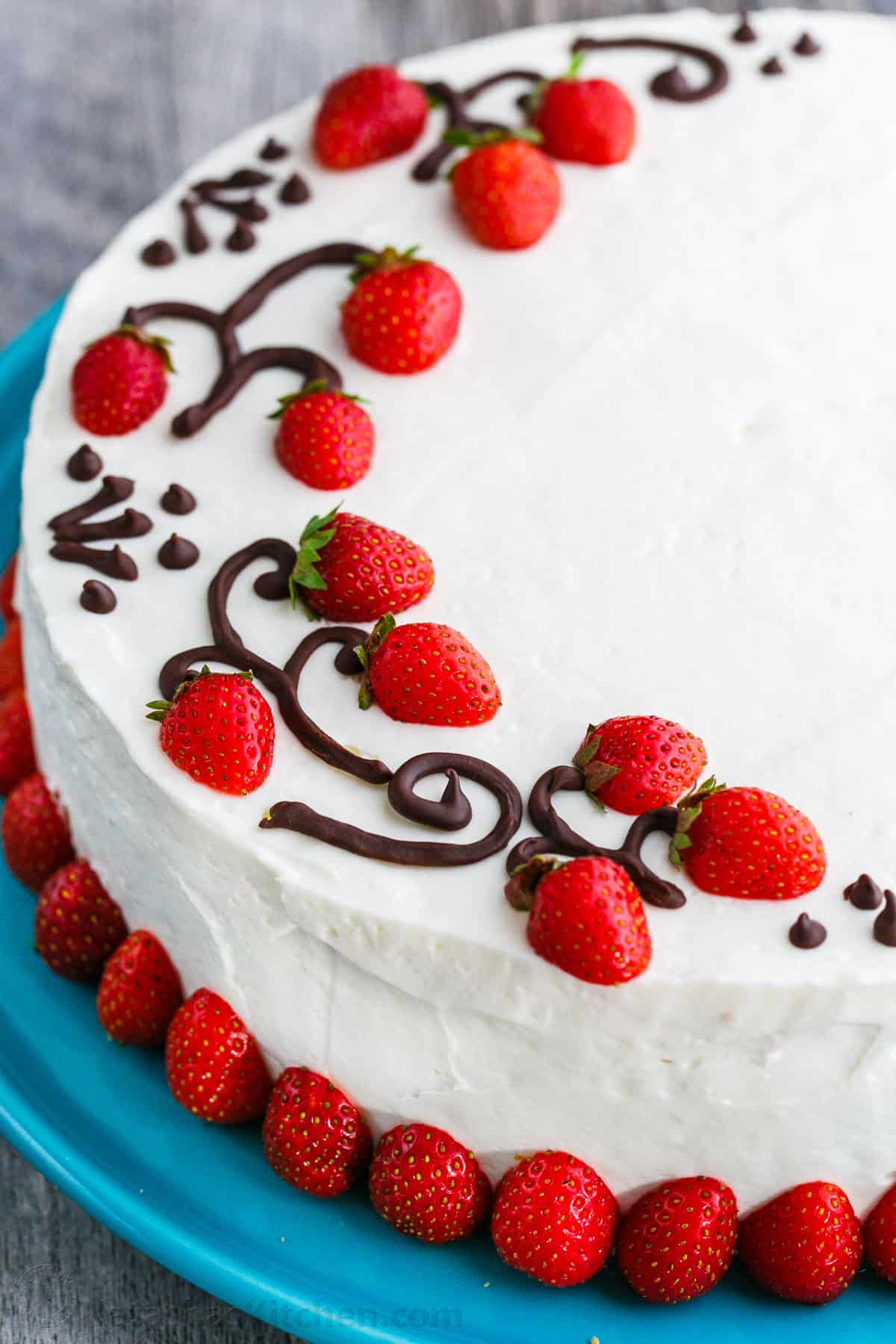 Strawberry cake decorated with fresh strawberries and piped chocolate