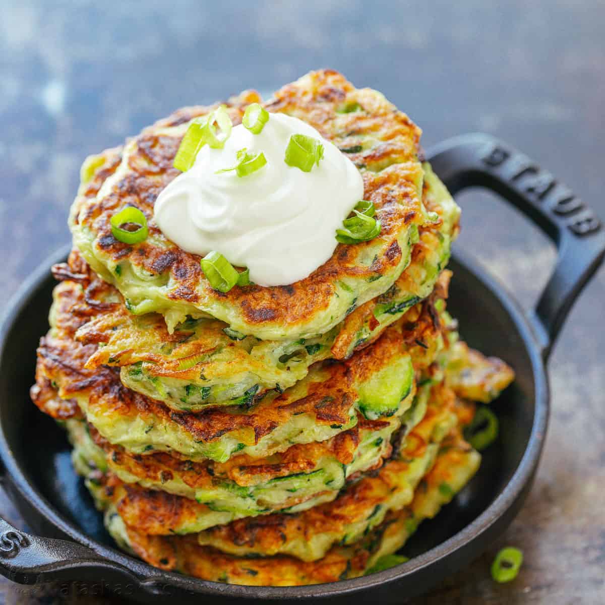 zucchini fritters stacked on a serving plate