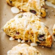 Baked Blueberry Scones on a baking sheet drizzled with glaze