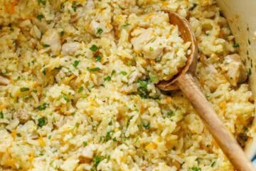 large dutch oven with creamy chicken and rice casserole mixed with a large wooden spoon