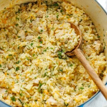 large dutch oven with creamy chicken and rice casserole mixed with a large wooden spoon