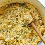 creamy chicken and rice recipe in a Dutch oven with large wooden spoon scooping casserole
