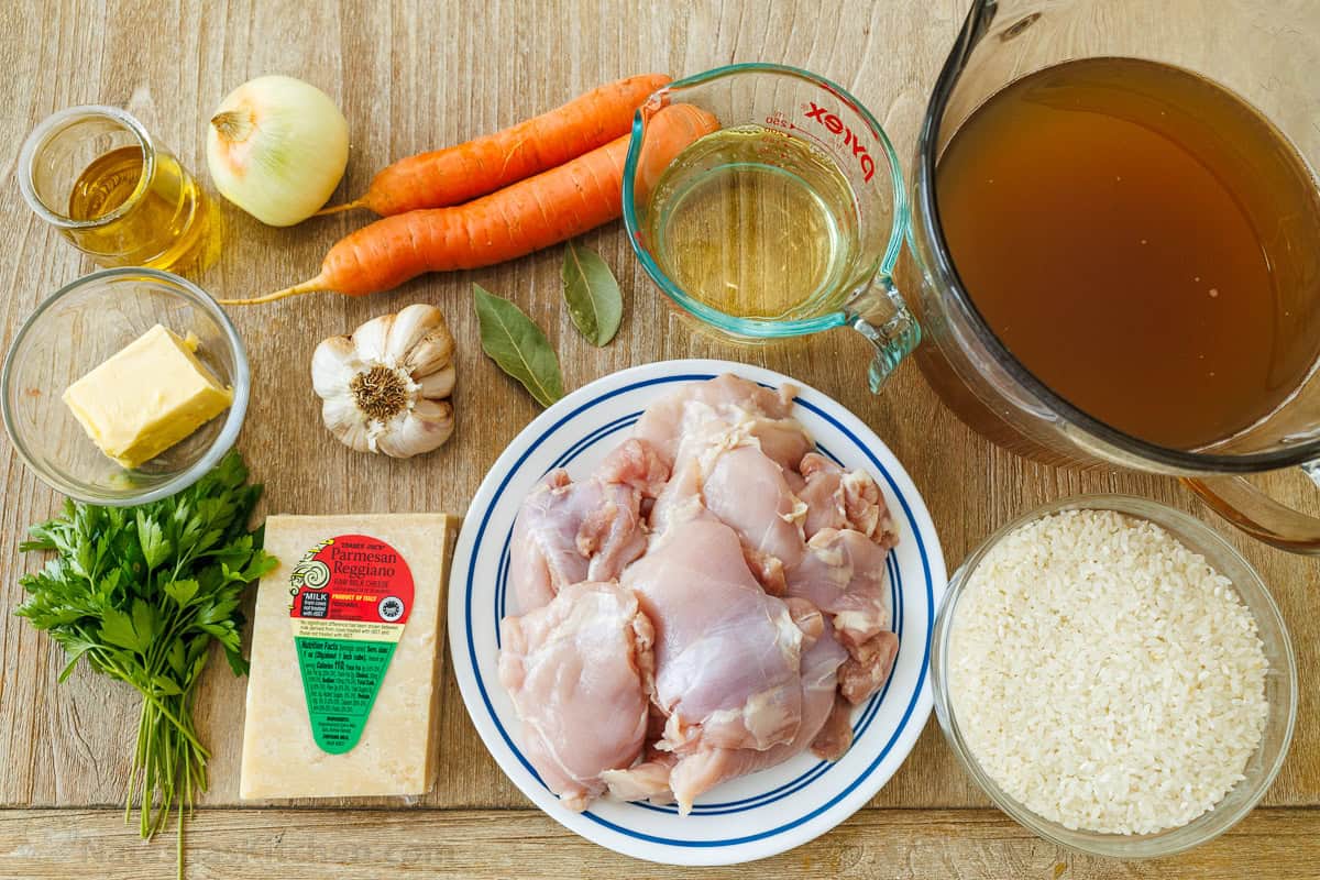 Ingredients for chicken and rice including chicken thighs, rice, broth, vegetables, and Parmesan