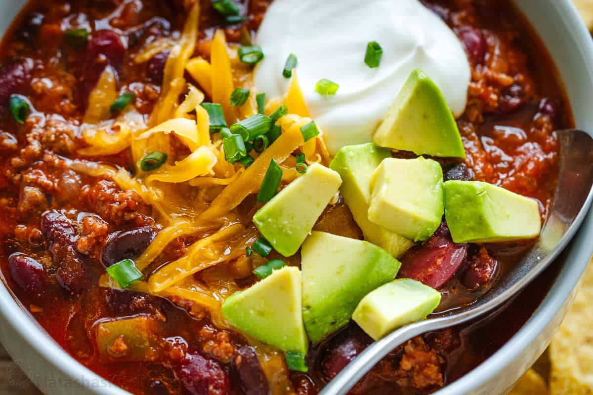 Slow cooker beef chili with avocado, cheese and sour cream toppings