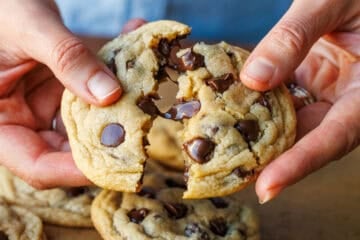 Breaking a soft chocolate chip cookie in half to show gooey morsels of chocolate