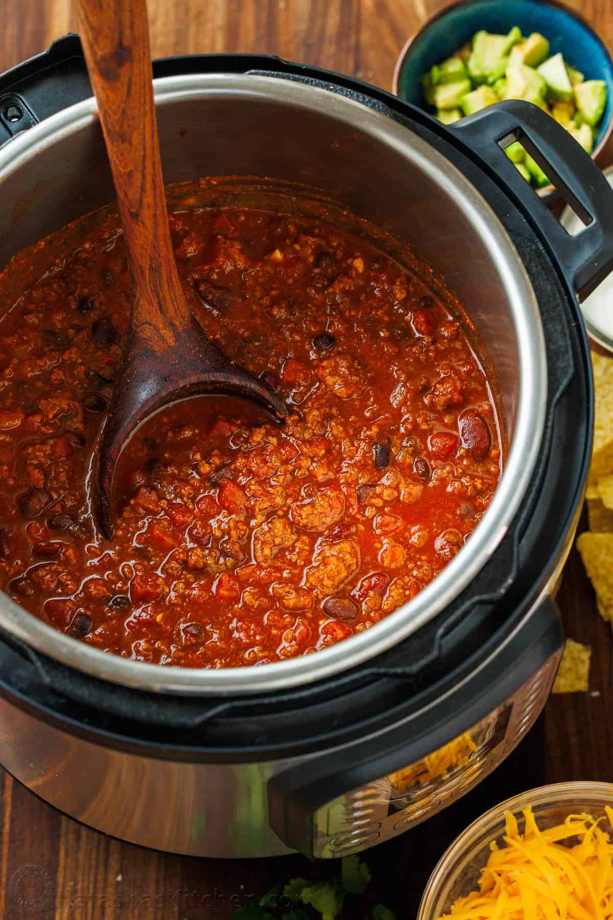 Cooked beef and bean chili in the Instant Pot with a wooden spoon