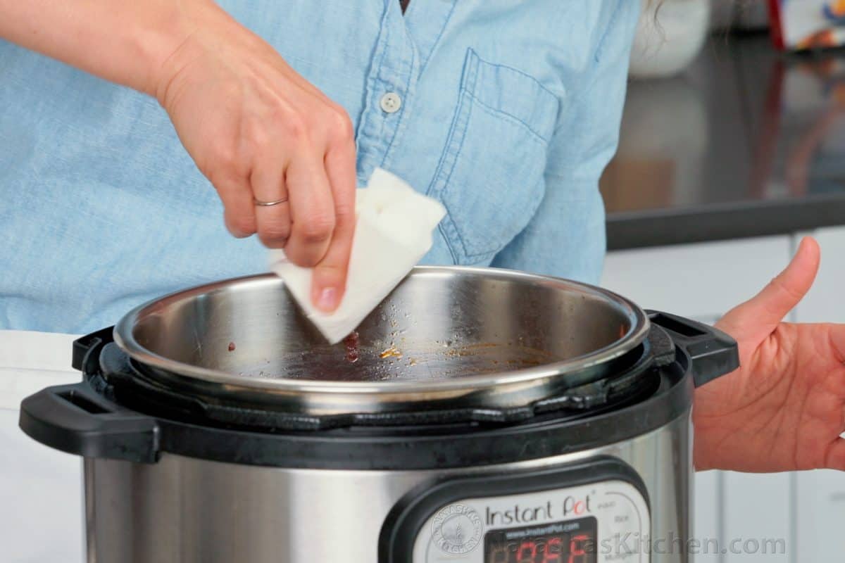 Wiping the rim of the Instant Pot inner pot with a paper towel before sealing the lid
